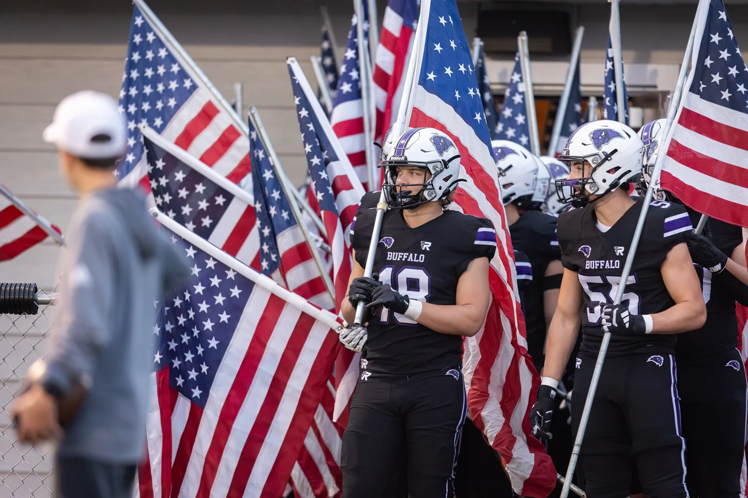 Bison carring their flags onto the field